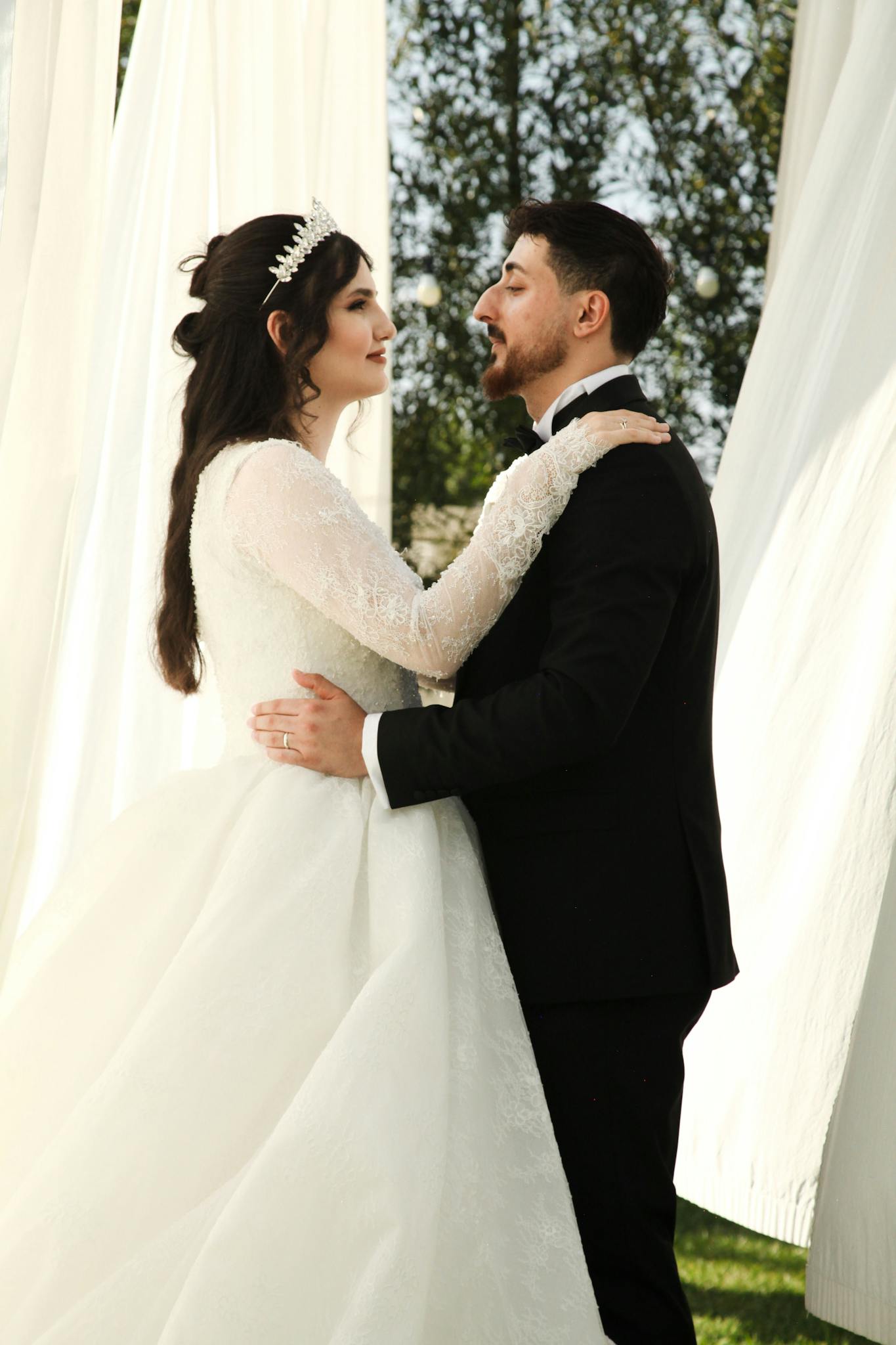 Bride and groom embrace outdoors with elegance and love.